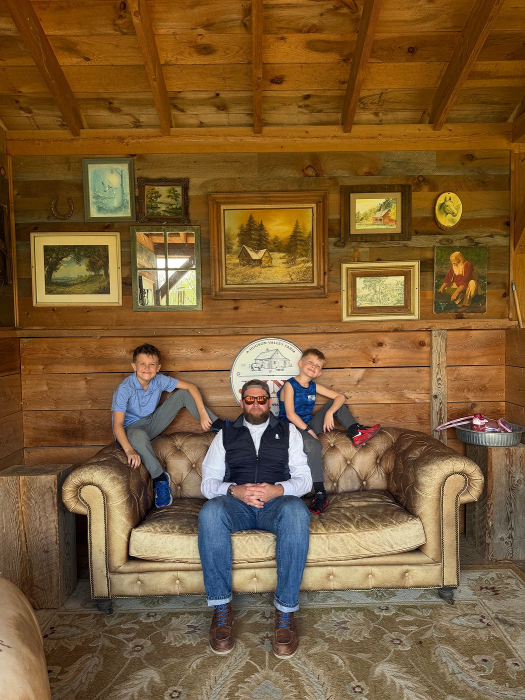 Taylor sitting on a leather sofa with his two boys perched on the back